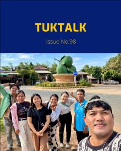 TukTalk issue 98 cover above a selfie of TukTuk staff and friends posing beside a roundabout monument