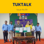 TukTalk issue 99 cover above a photo of officials and TukTuk staff holding signed agreement folders at a table
