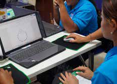 Teachers gather around a laptop on a table, learning to use computers at a workshop.