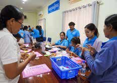 Teachers sit around a table crafting with paper and baskets of supplies during a play-based learning activity.